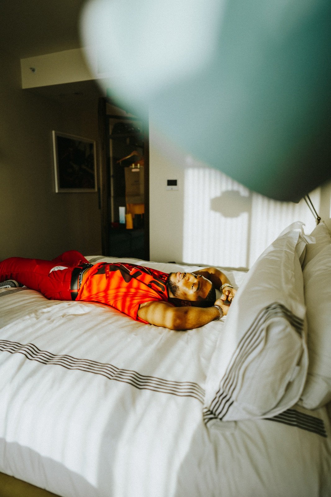 Orange outfit, lying on a hotel bed
