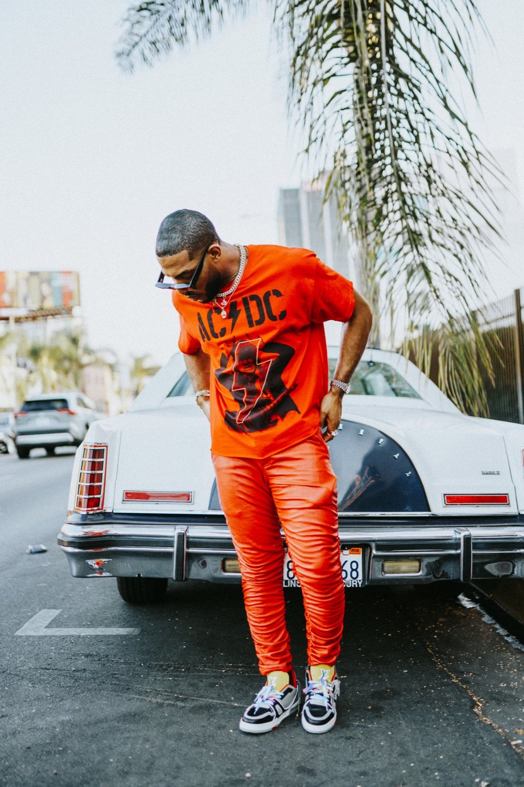 Orange outfit against a white car